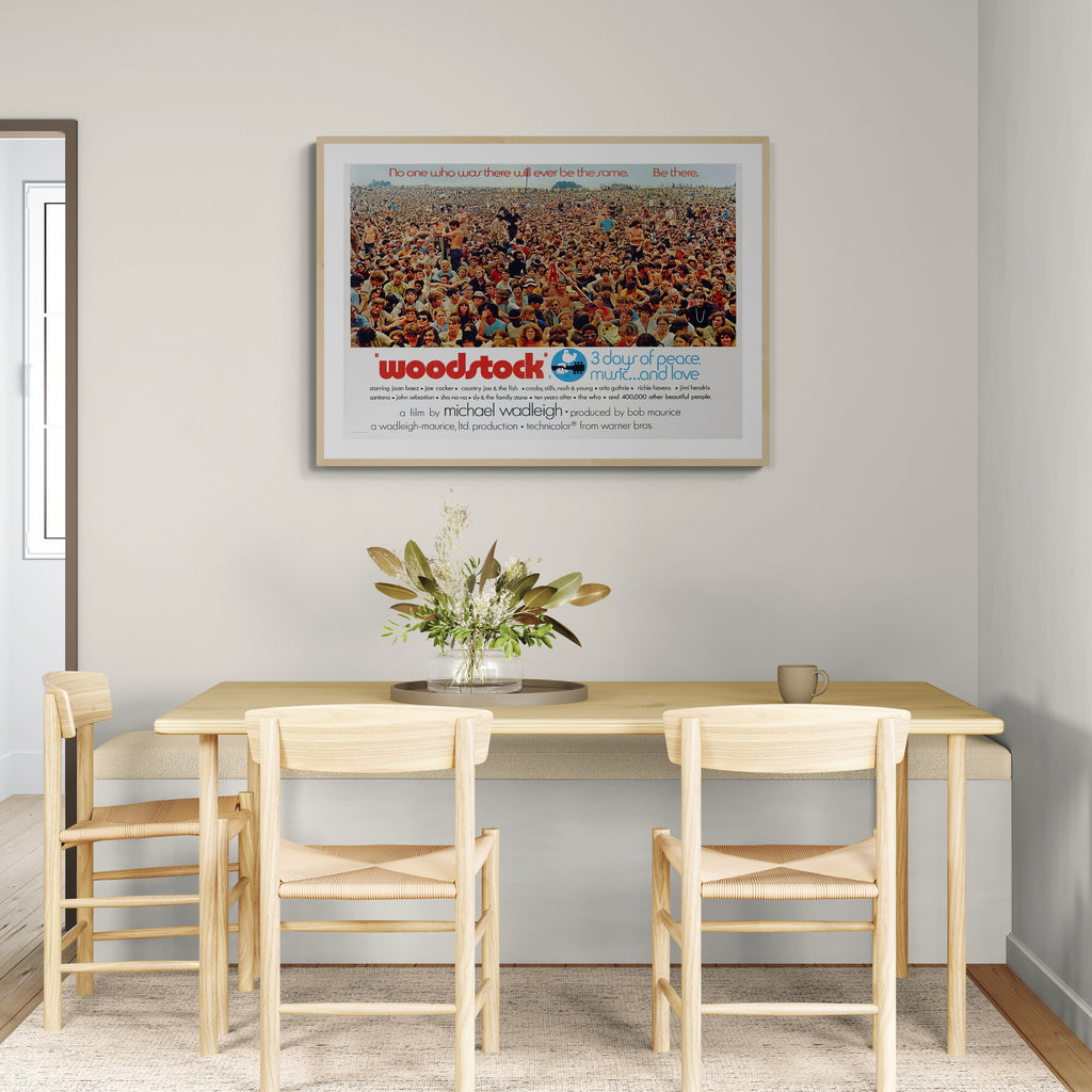 Dining room with a wooden table and chairs, featuring a framed Woodstock poster on the wall.